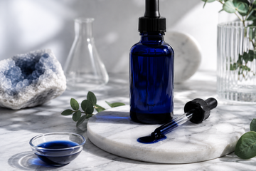 Metylenblått i en glasflaska, ståendes på marmorbord med pipeett och flytande methylene blue i skål