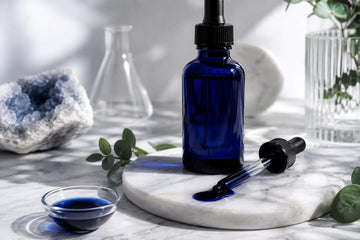 Metylenblått i en glasflaska, ståendes på marmorbord med pipeett och flytande methylene blue i skål